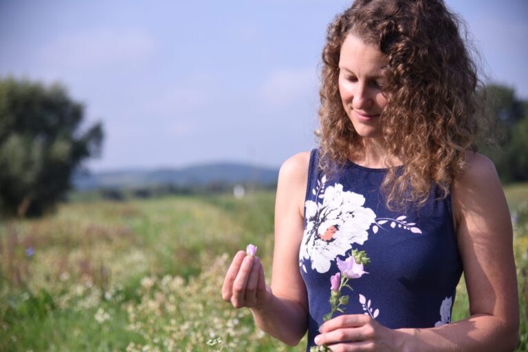 Elisabeth Teufner betrachtet eine Blüte auf der Wiese