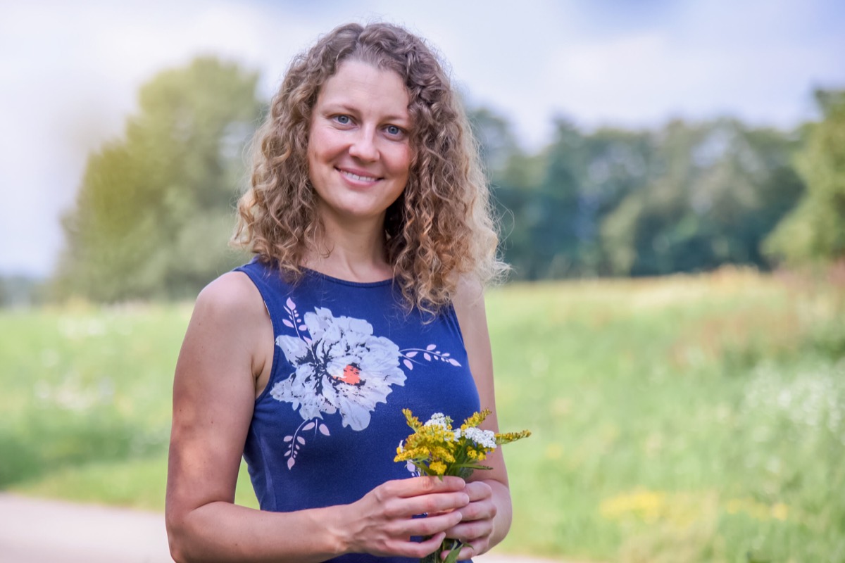 DI Elisabeth Teufner mit einem Kräuterstrauß auf der Wiese